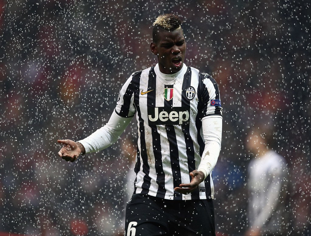 Paul Pogba standing in a sleek outfit, with a football stadium in the background.