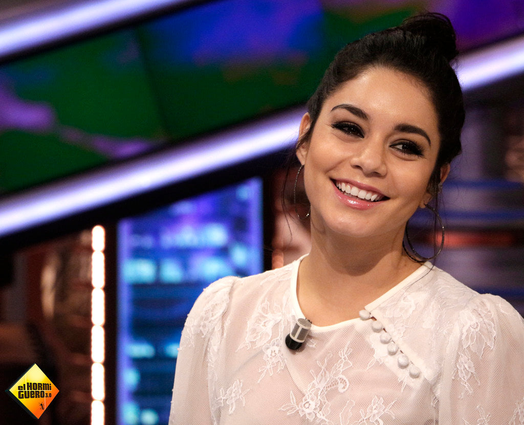 Vanessa Hudgens posing elegantly in a scenic garden setting, wearing a trendy outfit.