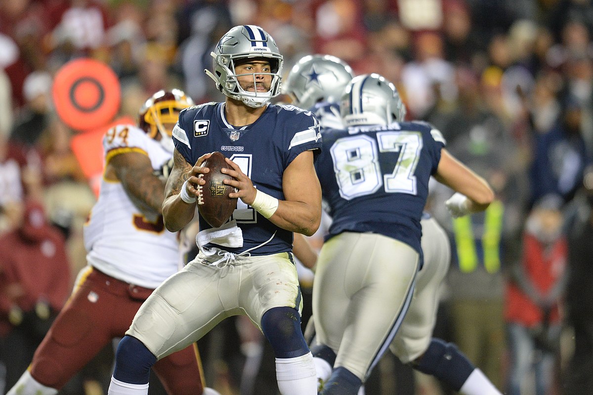 Dak Prescott standing confidently in a stadium, wearing his Dallas Cowboys uniform