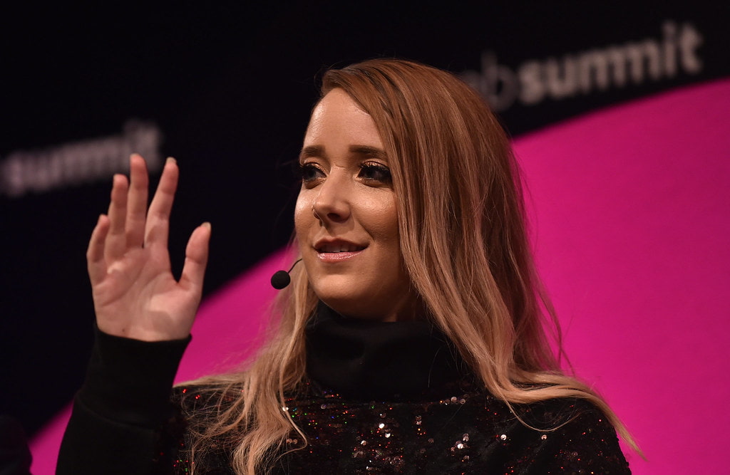 Jenna Marbles, in a black high-neck with open hair, addressing the audience at a press conference