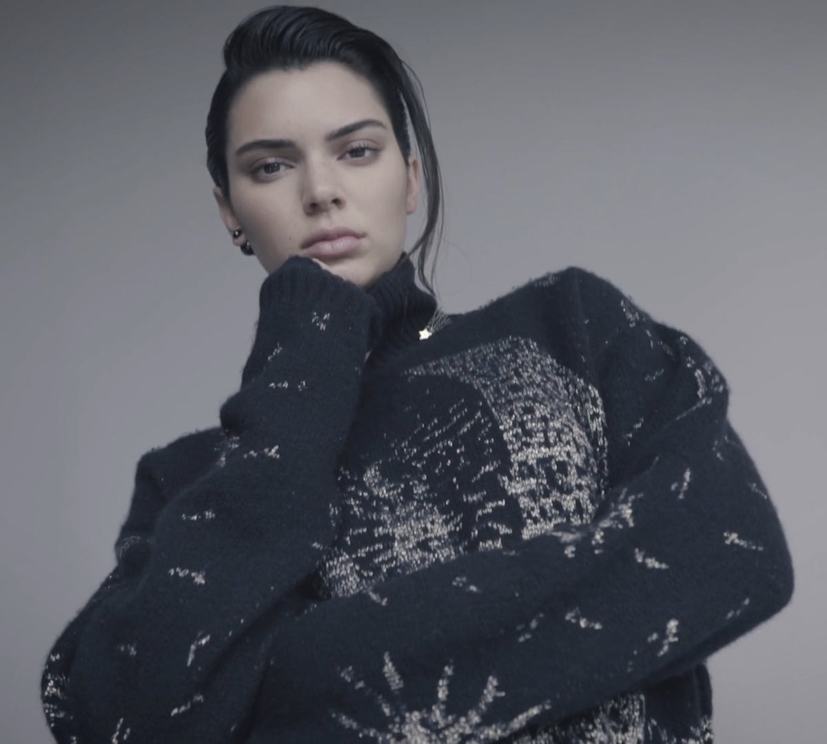 Kendall Jenner posing stylishly in a trendy outfit, with her hair styled sleekly and a plain backdrop.
