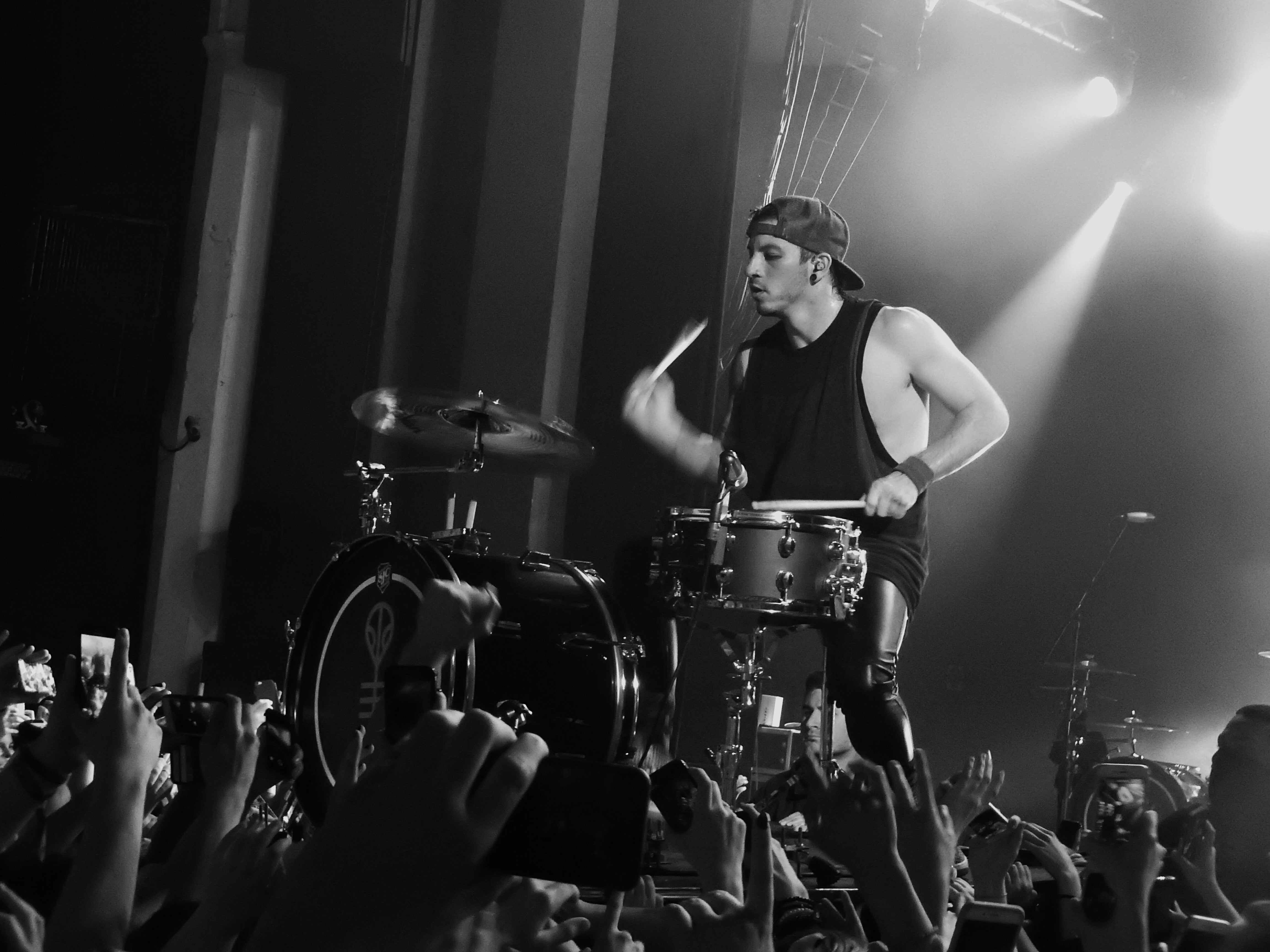 Black and white picture of Josh Dun playing drums at the concert.